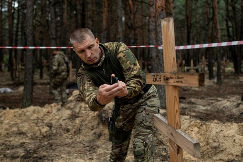 oleg-kotenko-the-commissioner-for-issues-of-missing-persons-under-special-circumstances-uses-his-smartphone-to-film-the-grave-a-ukrainian-soldier-in-izium-ukraine-thursday-sept-73b8d65d4e61ecba127e80c74b22a4451663343107.jpg