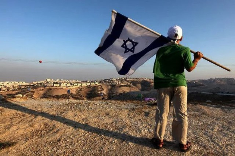 an-israeli-man-looks-for-a-new-area-in-west-bnak-where-to-put-this-flag-as-a-mark-of-possession-of-the-land-bf5b765ad4ca3ed2c9082bc6bfce4fef1697911772.jpg
