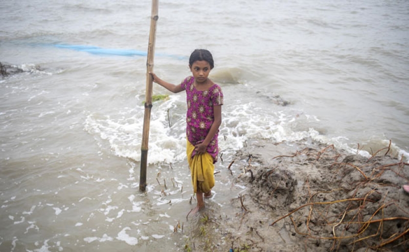 a-young-girl-trying-to-cross-a-flooded-road-in-bangladesh-following-the-wake-of-cyclone-remal-391a4721ccb542c93a0d2373ef87ee621734751202.jpg